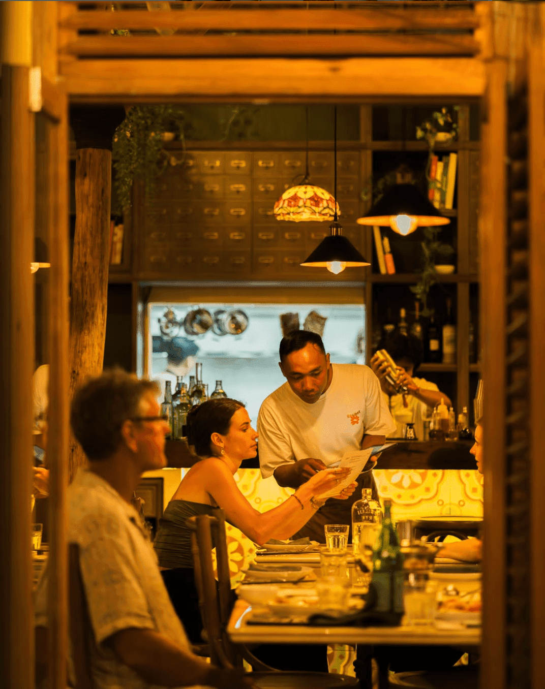 People consulting the menu in a thai restaurant getting advices from the waiter
